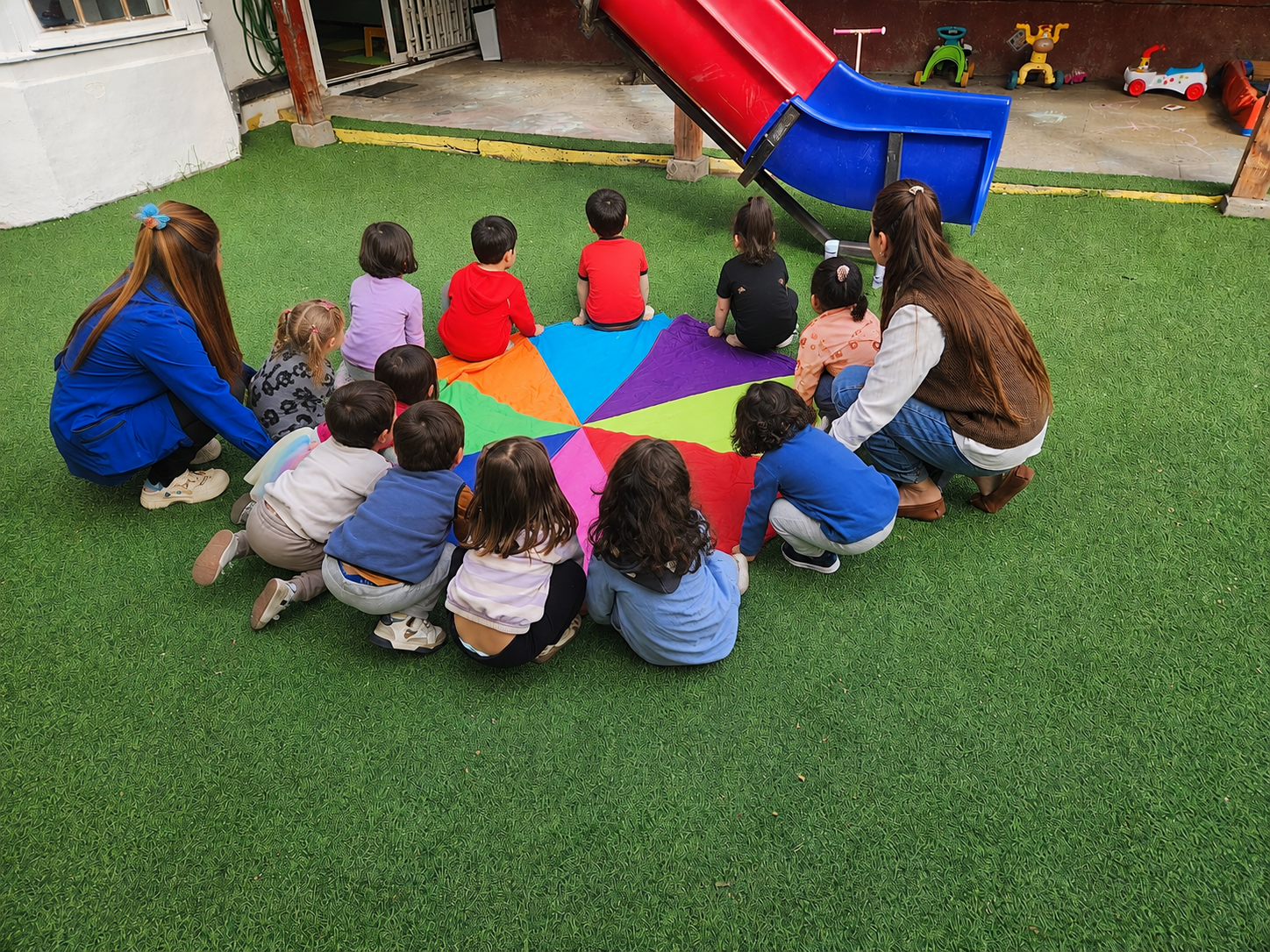 Niños jugando con telas de colores en una actividad sensorial.